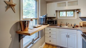 A compact kitchen with a wooden shelf, white cabinets, a star decoration, and a window.