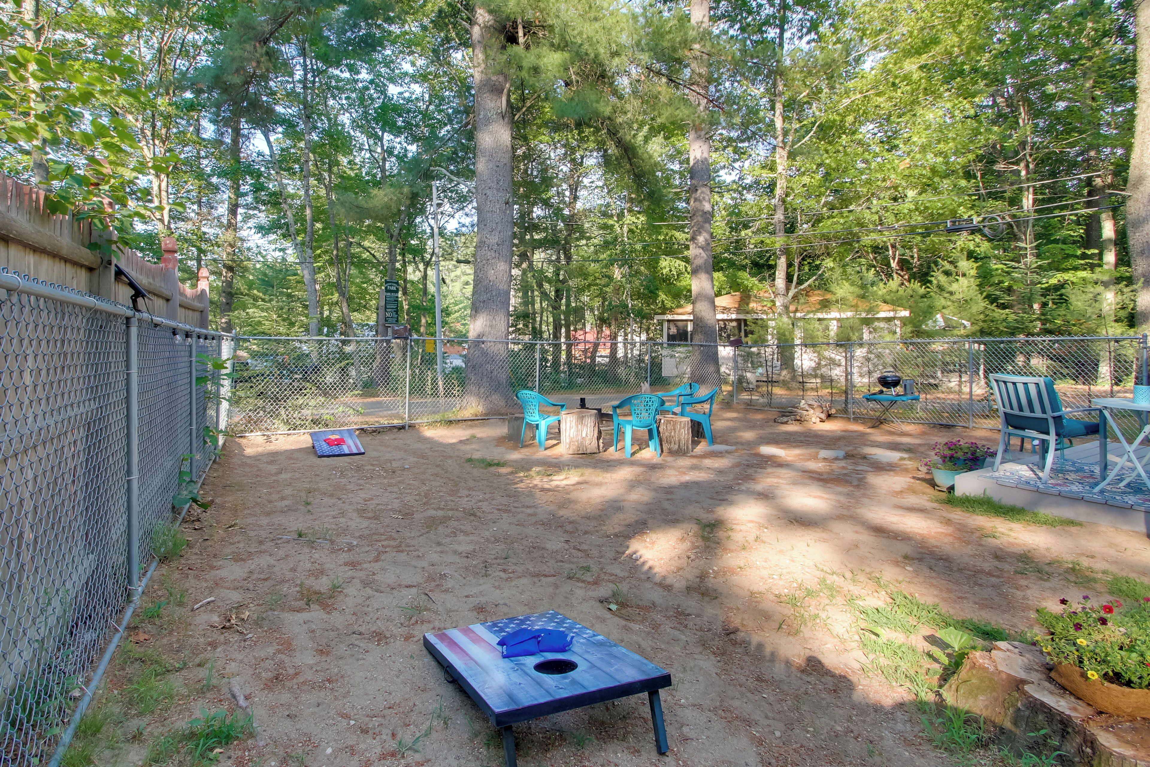 A fenced backyard with a wooden table and chairs, a wooden stump planter, and a metal fence.