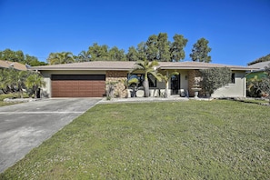 A single-story house with a garage, a front porch, and a well-maintained lawn. - Pet-friendly Oasis w/ Deck & Fire Pit in Bokeelia! (Bokeelia)