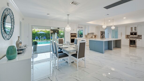 A modern kitchen with white cabinetry, a central island, and pendant lighting. - Pool & Spa: Luxe Home in Naples! (Naples)