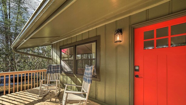 A wooden deck with rocking chairs and a red door. - Brevard Outdoor Retreat at Connestee Falls (Brevard)
