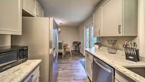 A kitchen with a microwave, refrigerator, and sink. There is a dining area with a table and chairs. - Brevard Outdoor Retreat at Connestee Falls (Brevard)