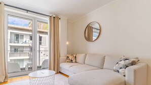 A modern living room with a beige sofa, a round mirror, and a small white table. - Cozy Santa Cruz (Santa Cruz)