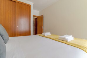 A hotel room with a bed, a wooden wardrobe, and a door leading to another room. - Cozy Santa Cruz (Santa Cruz)