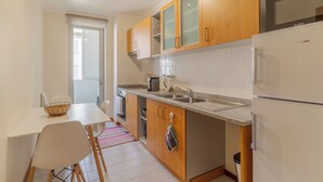 A compact kitchen with wooden cabinets, a white refrigerator, a sink, and a dining area with a table and chairs. - Cozy Santa Cruz (Santa Cruz)