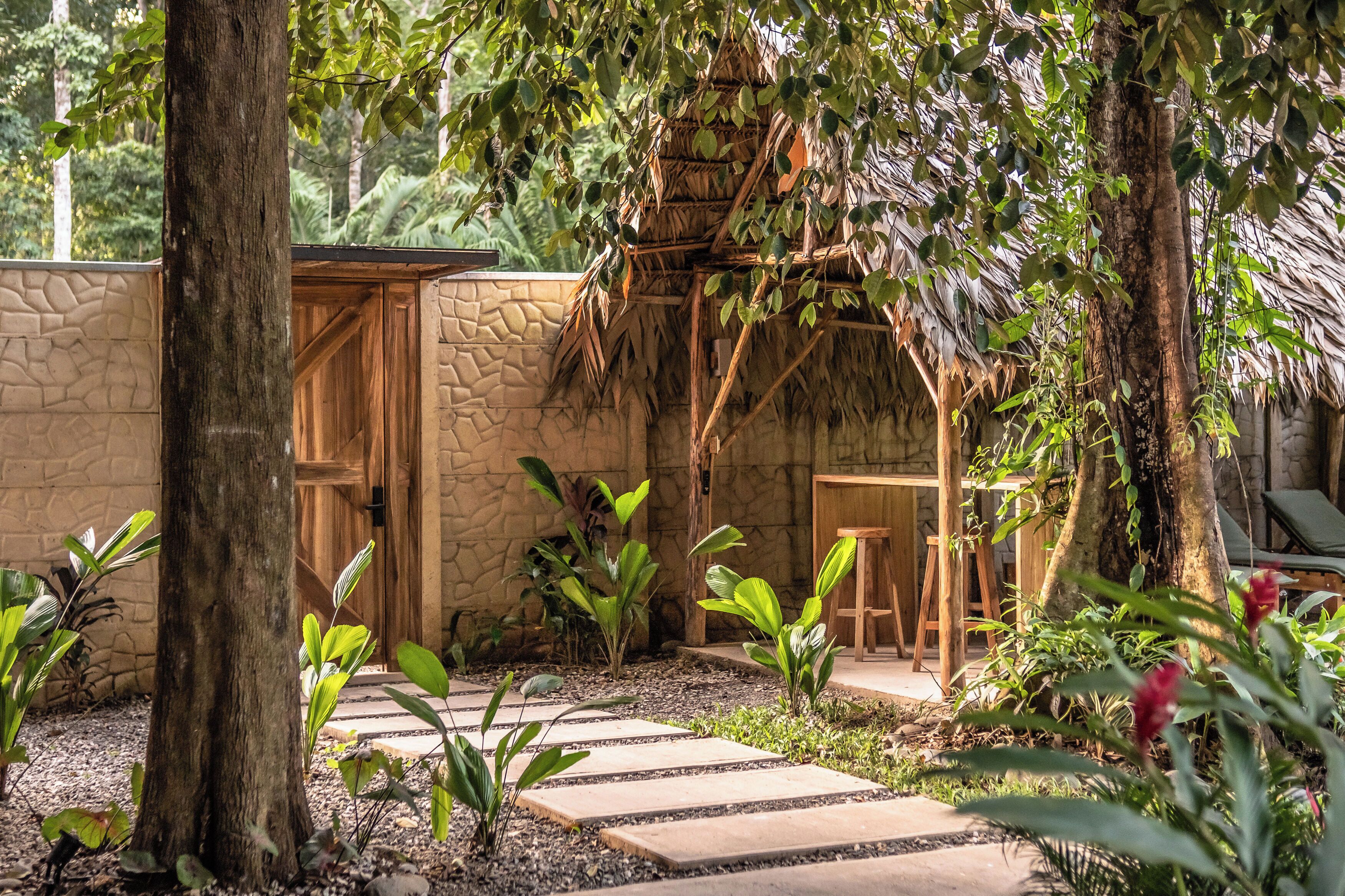 A garden with a stone wall, wooden pergola, and a small wooden structure.