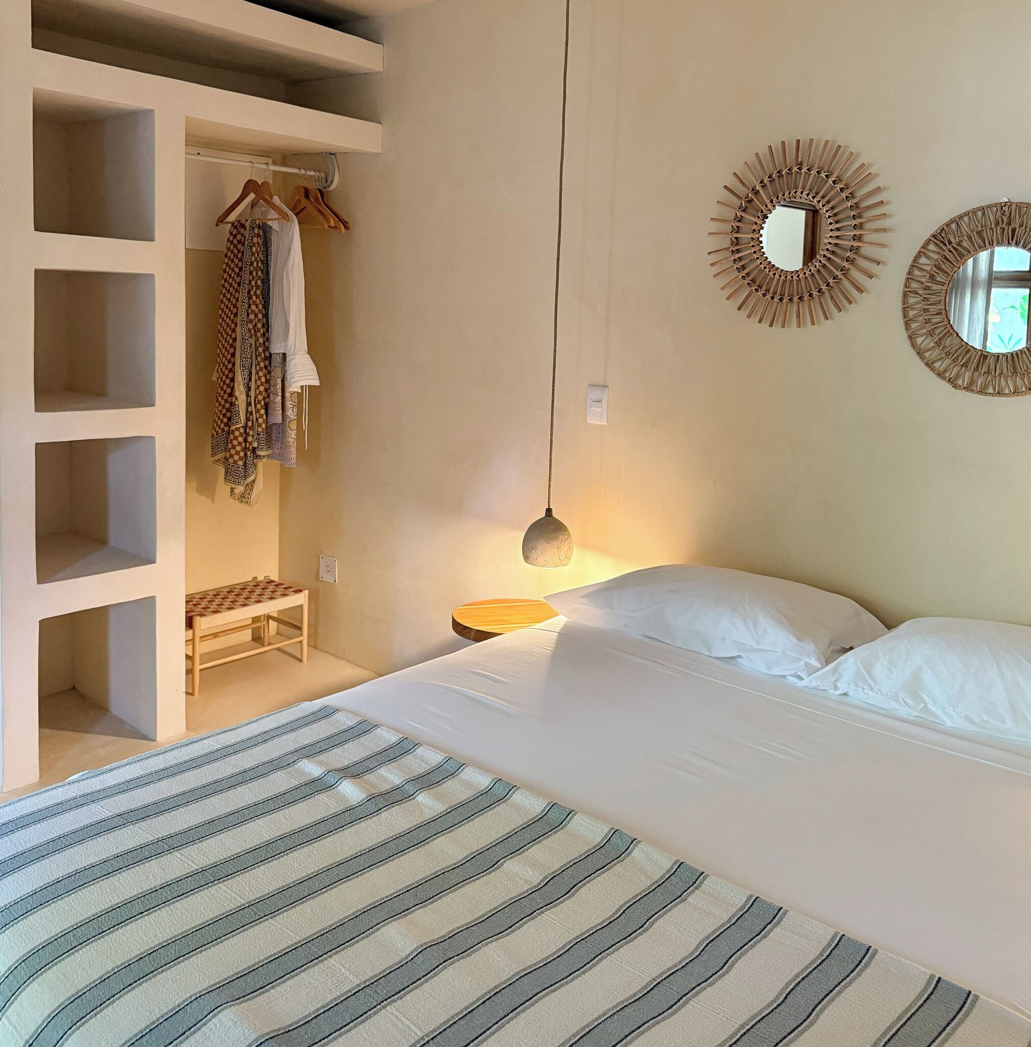 Ein Schlafzimmer mit Bett, einer Garderobe, einem kleinen Tisch und zwei Wandspiegeln.