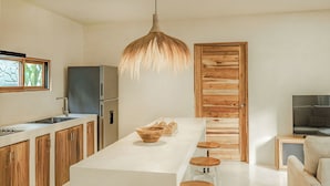 Une cuisine moderne dotée d’un îlot central, de meubles en bois, d ’un luminaire suspendu et d’une porte en bois.