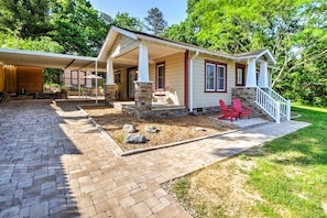 A house with a covered patio, stone steps, and a small garden area with rocks and a lawn. - Lovely Cottage w/ Sauna & Fire Pit Near Asheville! (Swannanoa)
