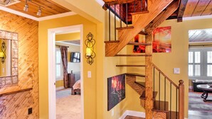 A wooden staircase with a modern design, a yellow wall, and a cozy living area with a couch and a coffee table. - Lovely Cottage w/ Sauna & Fire Pit Near Asheville! (Swannanoa)