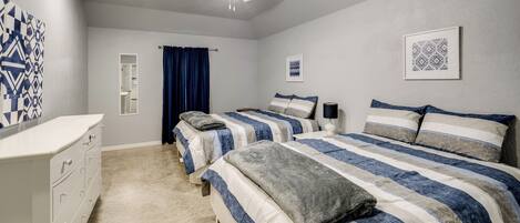 A bedroom with two beds, a ceiling fan, and a dresser.
