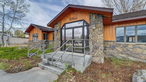 A lodge with a stone facade, wooden trim, and large windows. - Spacious Home 10 Minutes to Ten Sleep Canyon! (Ten Sleep)