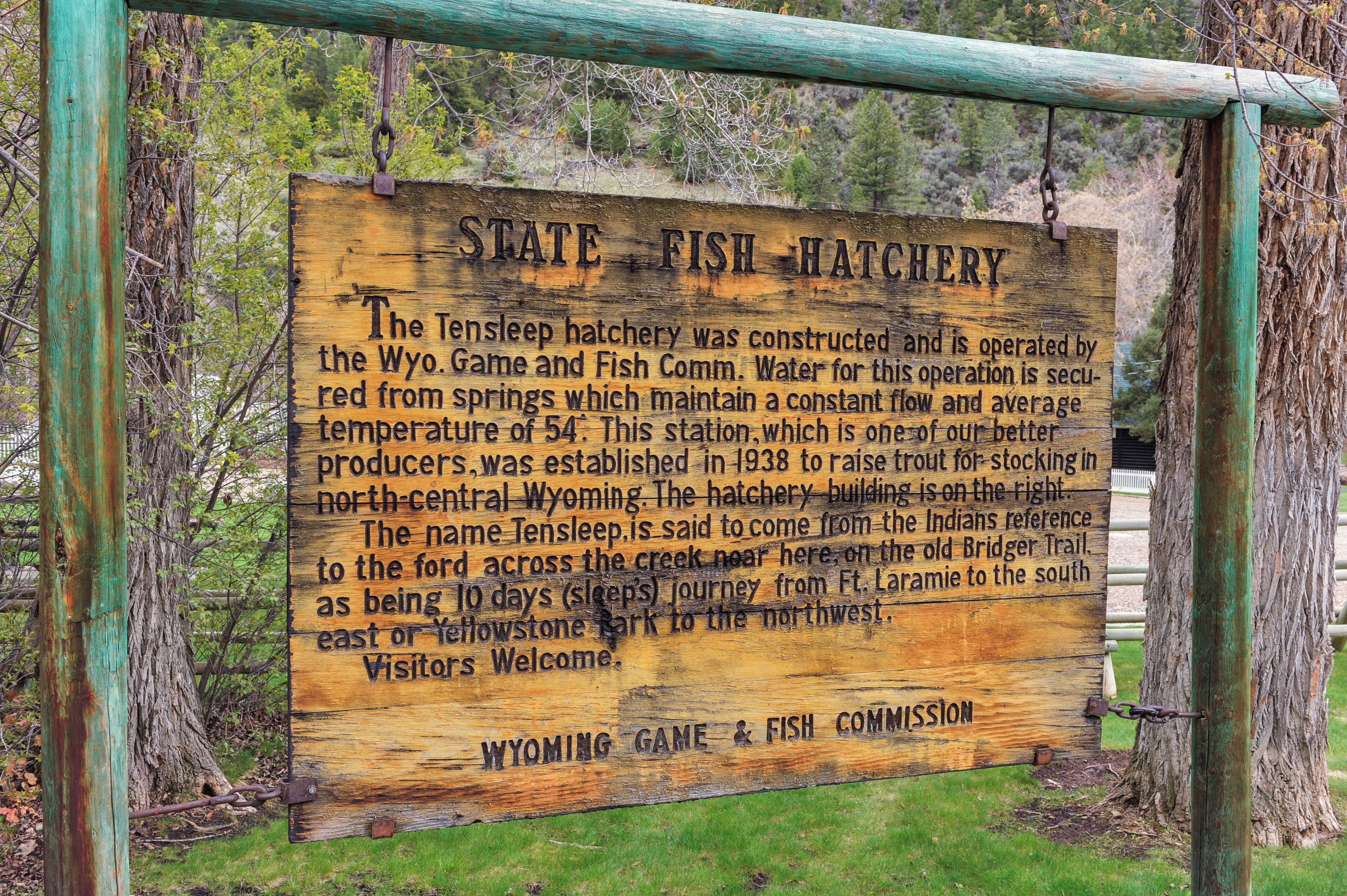 Et træskilt med tekst der beskriver Tensasleep-opdrætteri, drevet af Wyoming Game and Fish Commission, samt historiske og driftsmæssige detaljer.