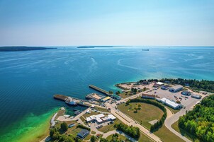 Vista aérea de una zona costera industrial con un puerto deportivo, edificios y agua azul cristalina.