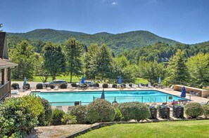 A swimming pool with lounge chairs and umbrellas, surrounded by lush greenery and hills in the background. - Chalet w/ Mtn Views & Golf Course Access! (Dillard)