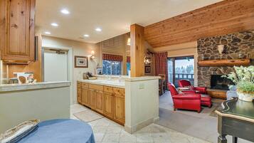 A kitchen with wooden cabinets, a central island, and a dining area with a red leather sofa.