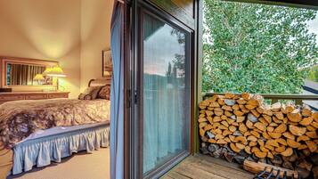 A bedroom with a bed, a nightstand, a lamp, and a window with a view of trees.