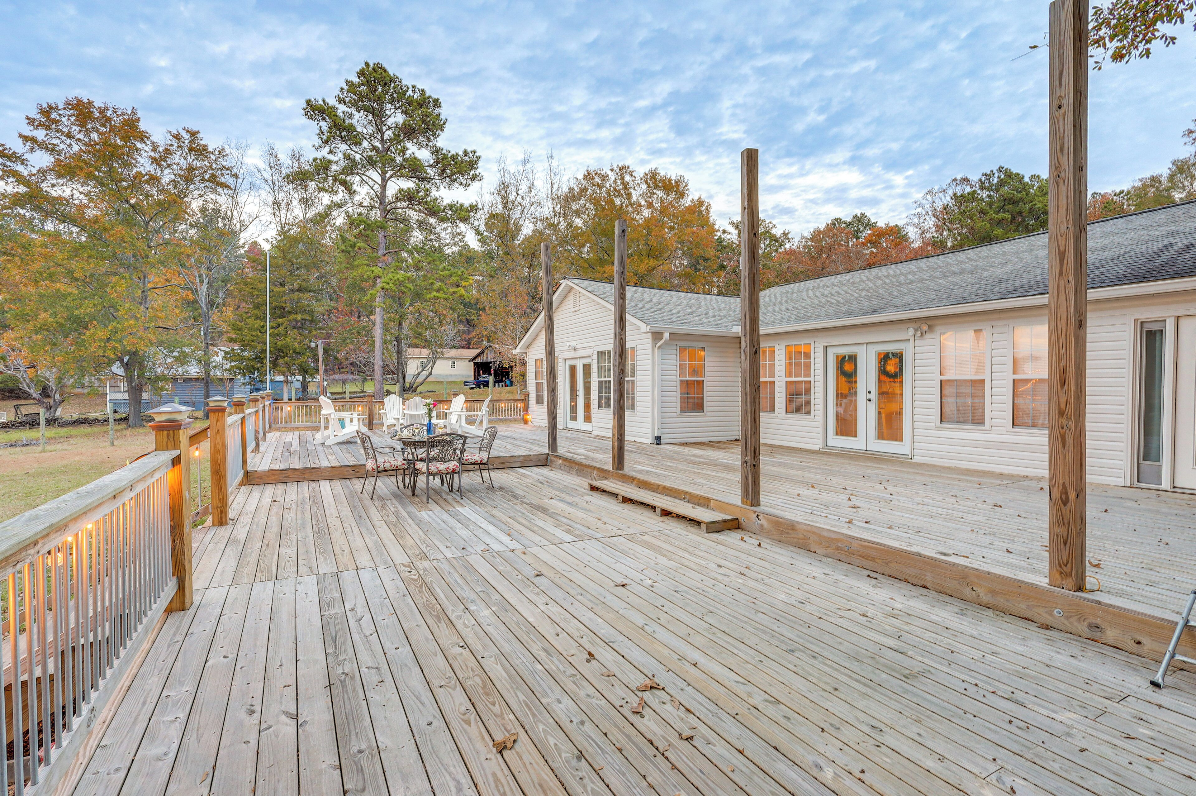 A wooden deck with a table and chairs, surrounded by a white building with windows and a door.
