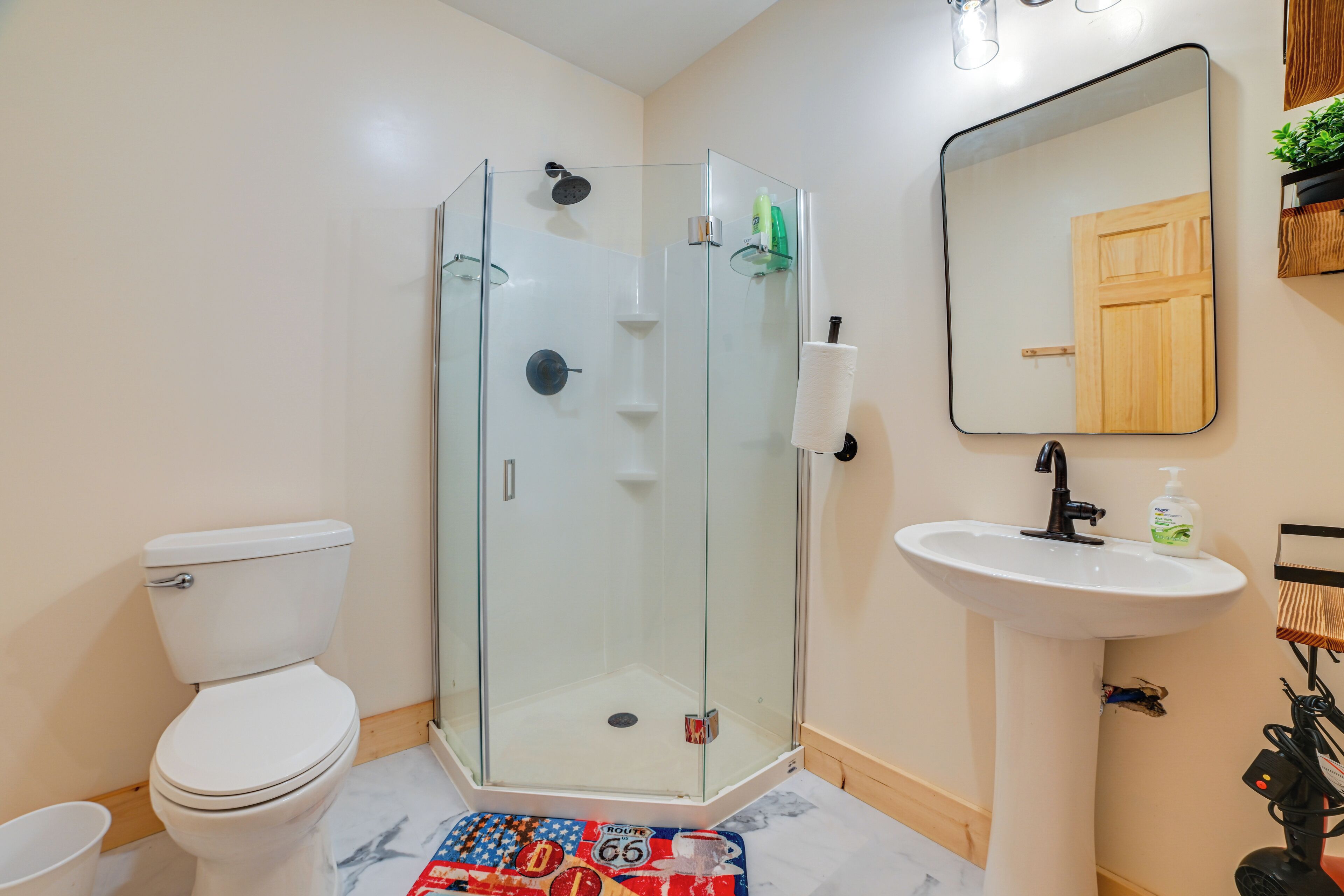 A bathroom with a glass-enclosed shower, a toilet, a sink, and a mirror.