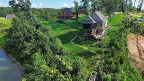 A large house with a deck and a river nearby. - Large Deck & Shared Dock: Cabin on Kentucky Lake! (Gilbertsville)