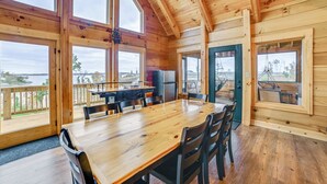 A wooden cabin with a dining area, large windows, and a view of the outdoors. - Large Deck & Shared Dock: Cabin on Kentucky Lake! (Gilbertsville)