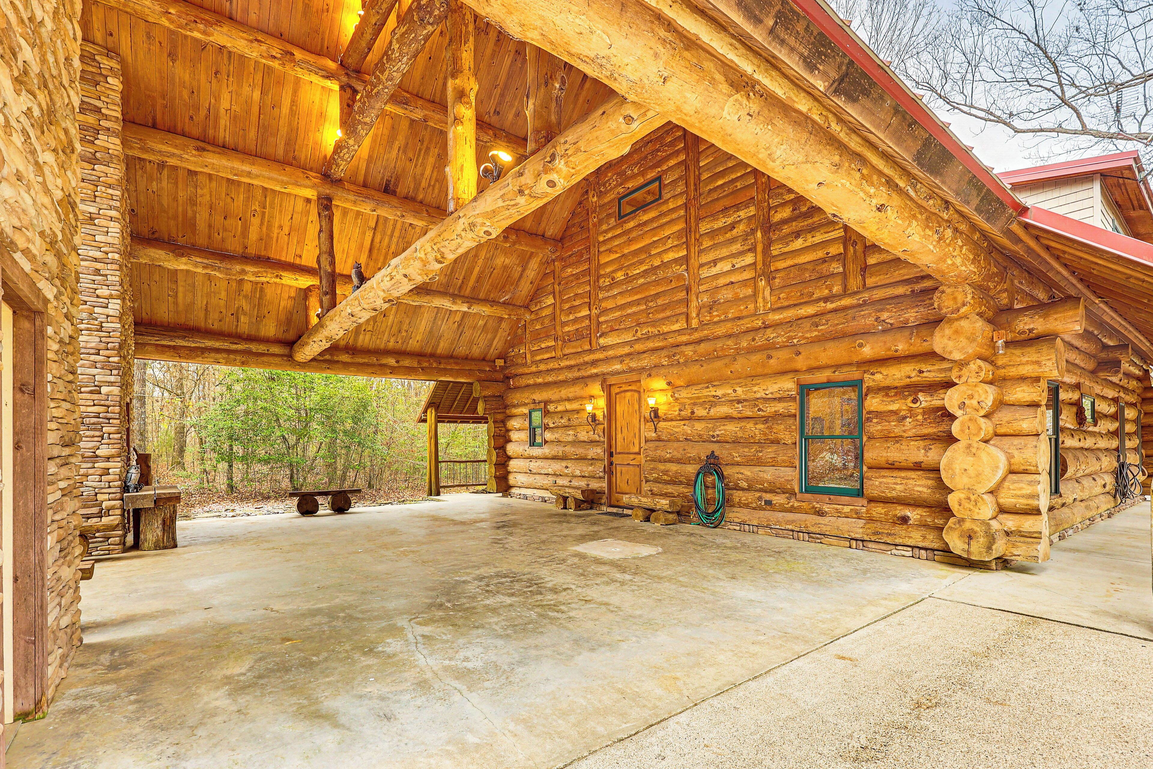 A log cabin with a stone exterior, a large open porch, and a concrete floor.