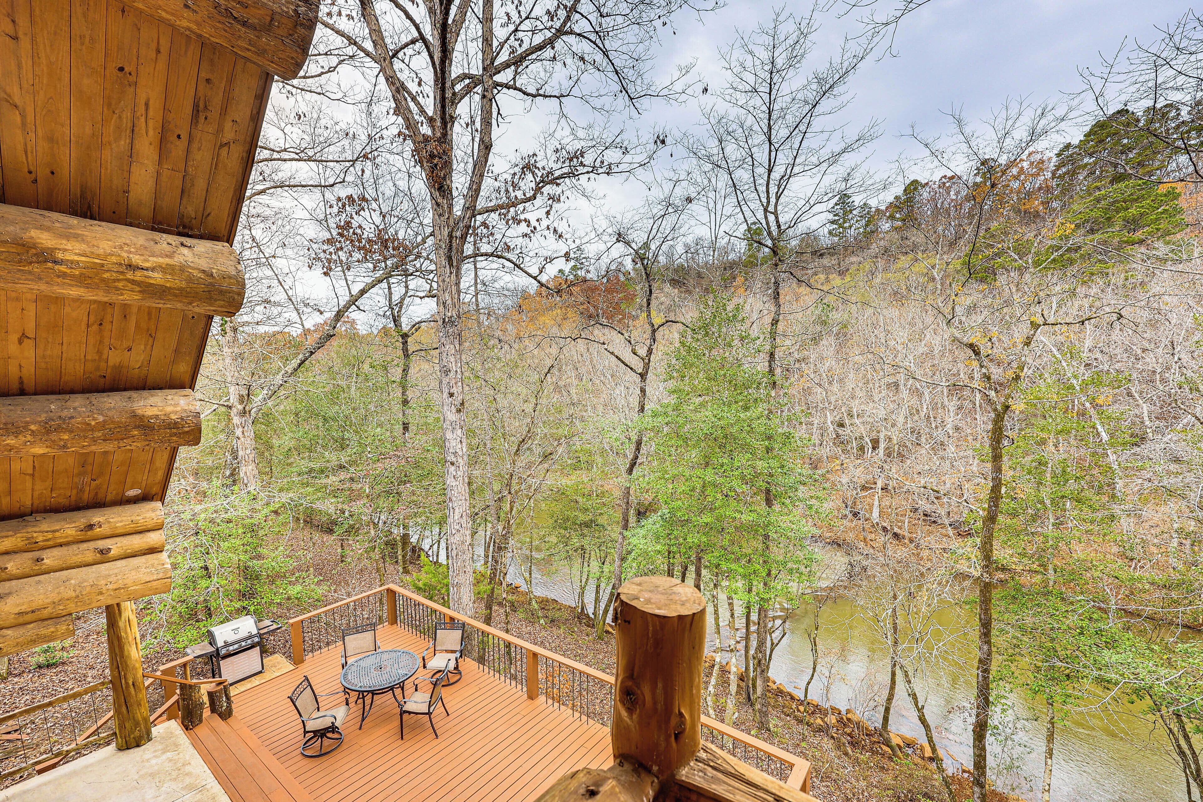 A wooden deck with outdoor furniture, overlooking a river and forested area.