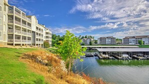 Een hotel aan het water met meerdere balkons, een steiger met boten en een gazon.