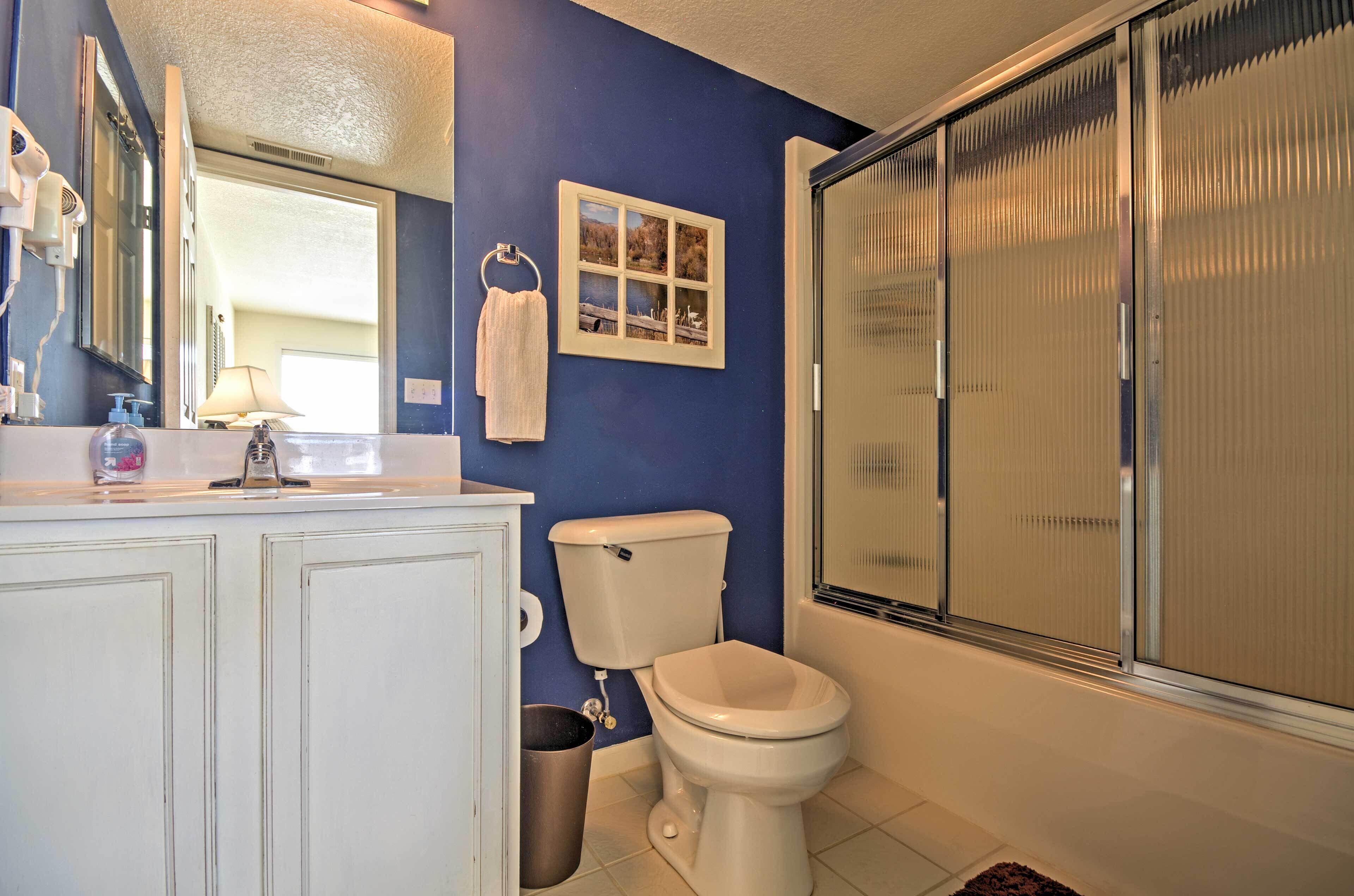 A bathroom with a toilet, sink, and mirror.