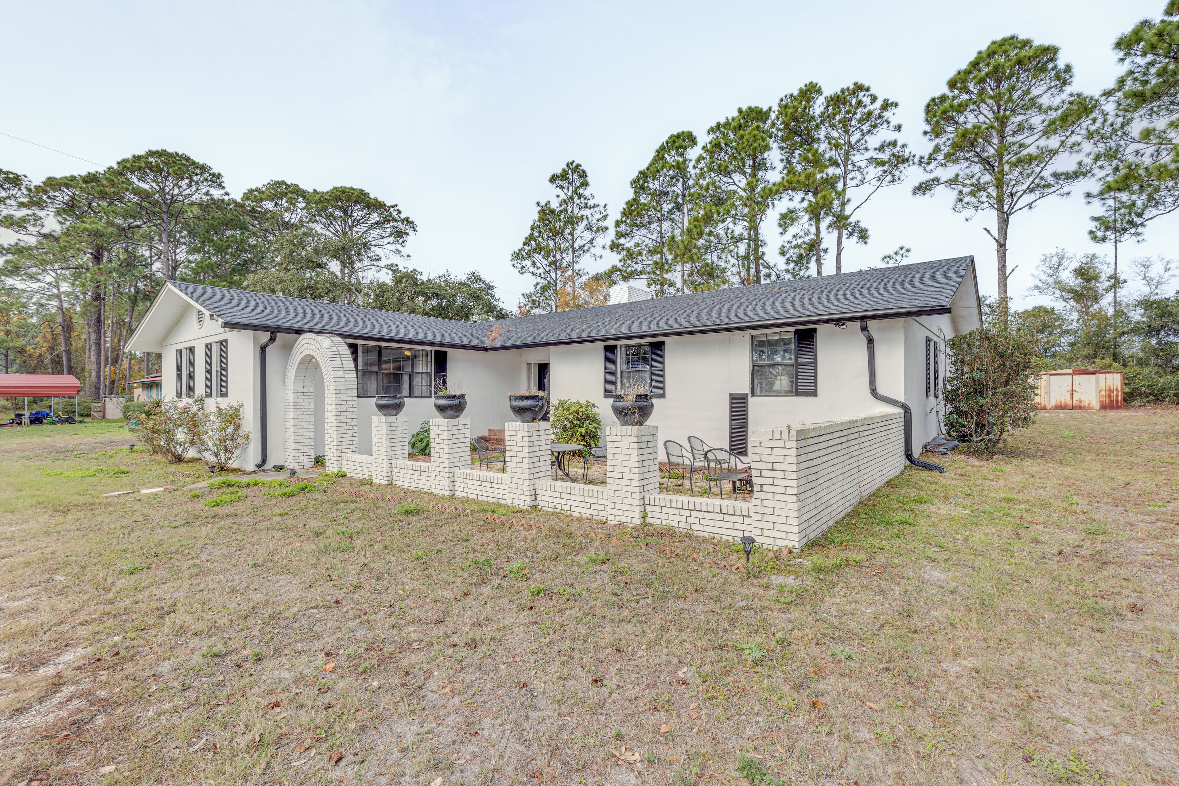A single-story house with a brick exterior, a flat roof, and a front porch with outdoor seating.