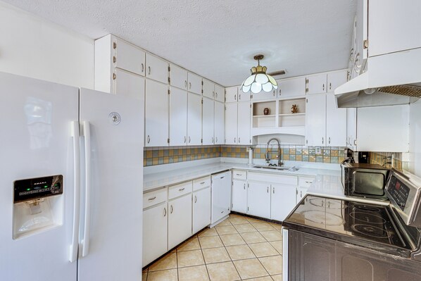 A kitchen with white cabinets, a refrigerator, a microwave, and a dishwasher. - Steps to Beach: Carrabelle Family Home w/ Patio! (Carrabelle)