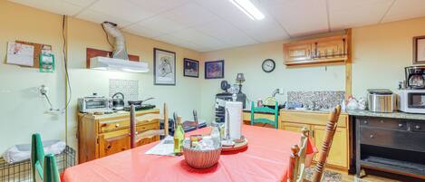 A kitchen with a dining table, chairs, a microwave, a stove, and various kitchen appliances.
