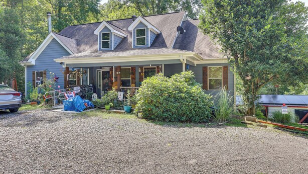 A two-story house with a covered porch, a gravel driveway, and a parked car. - Georgia Home w/ 2 Fire Pits & Creek Access! (Young Harris)