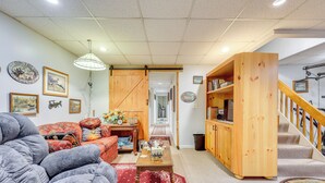 A cozy living room with a sofa, a coffee table, and a bookshelf. - Georgia Home w/ 2 Fire Pits & Creek Access! (Young Harris)