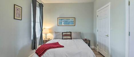 A bedroom with a large bed, a nightstand, a lamp, and a door.