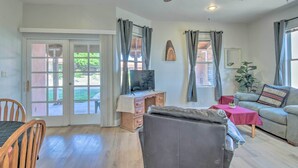 A living room with a sofa, a TV on a wooden cabinet, a dining table, and a ceiling fan. - Rejuvenating Retreat w/ Ideal Eloy Location! (Eloy)