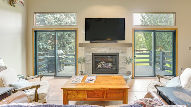 Un salón con chimenea, televisor y ventanas amplias.