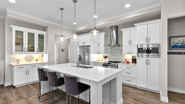 A modern kitchen with white cabinetry, a large island with bar stools, stainless steel appliances, and pendant lighting. - Sea Breeze Cottage - Private Home At The Shores 3 Bedroom Home (South Padre Island)