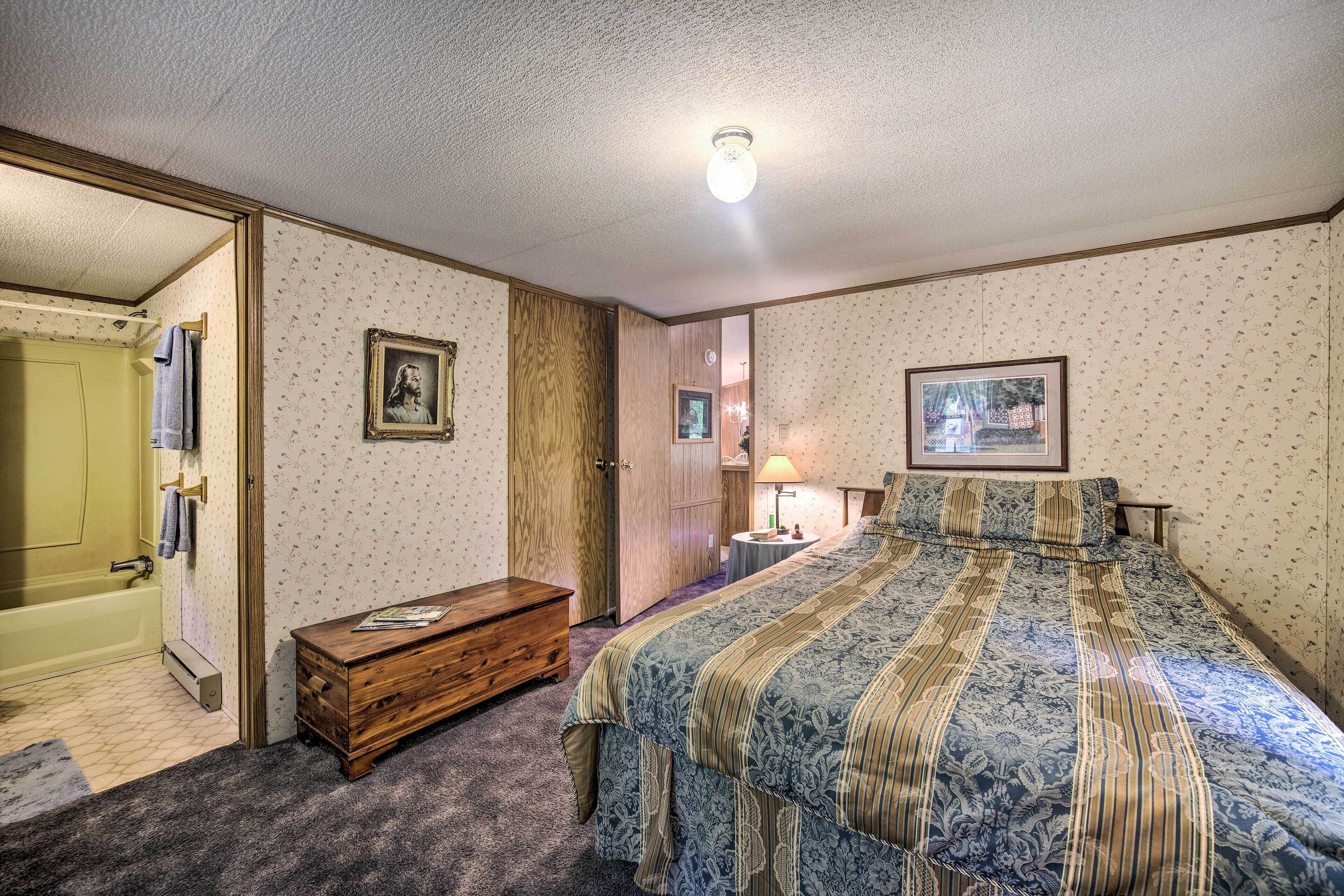 A bedroom with a bed, wooden dresser, and a door leading to a bathroom.
