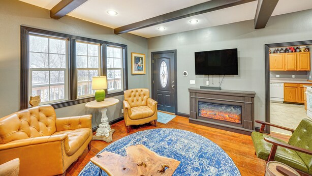 A living room with a fireplace, leather armchairs, a coffee table, and a television.