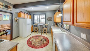 A compact kitchen with wooden cabinets, a refrigerator, a sink, and a dining area with stools.