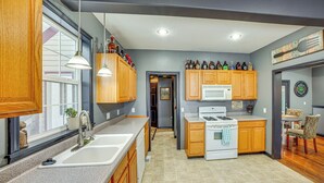 A modern kitchen with wooden cabinets, a white stove, and a countertop with various bottles.