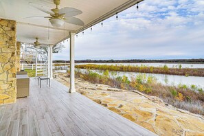 A covered outdoor area with stone flooring, a white railing, and a view of a lake. - Luxury Lakefront Retreat w/ Dock in Runaway Bay (Bridgeport)