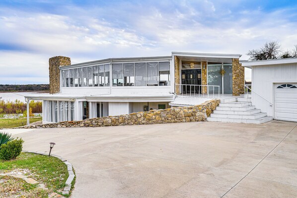 A modern two-story house with a stone facade, large windows, and a covered outdoor area. - Luxury Lakefront Retreat w/ Dock in Runaway Bay (Bridgeport)