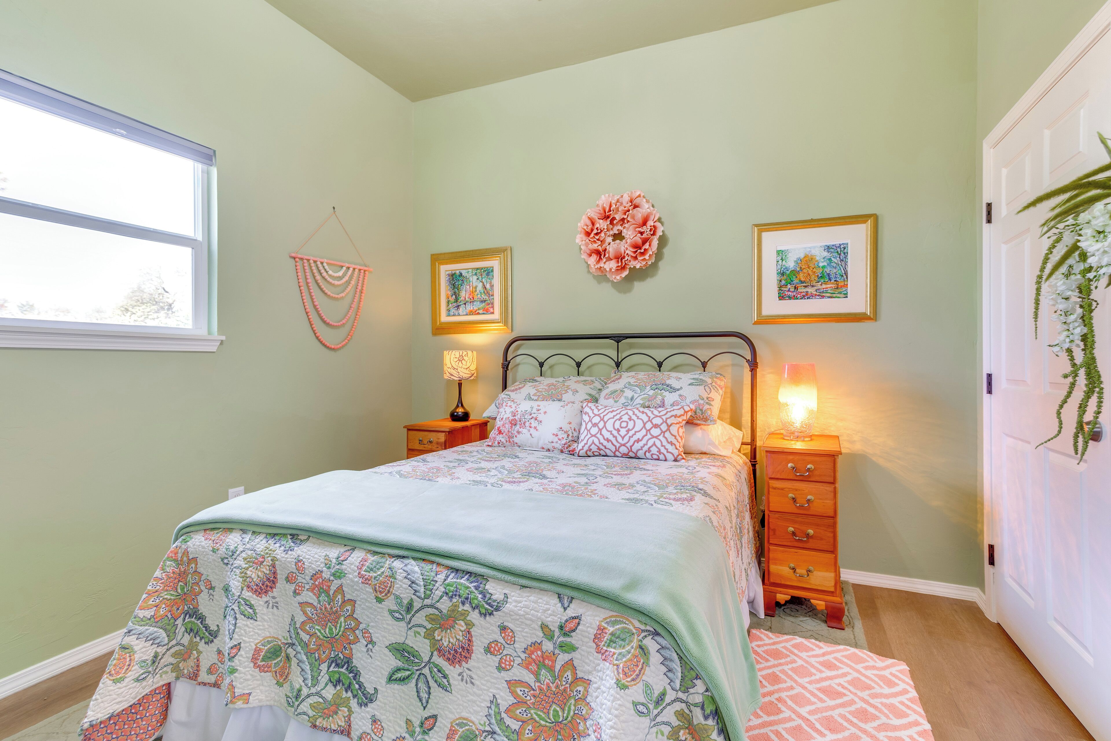 A neatly made bed with floral bedding, a bedside lamp, and a small wooden nightstand.