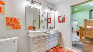 A bathroom with two sinks, a toilet, and a vanity with drawers.