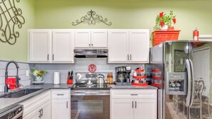 A modern kitchen with white cabinets, stainless steel appliances, and a red refrigerator. - 4 Mi to Lazy E Arena: Horse Lover's Haven w/ Grill (Guthrie)