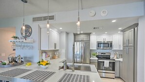 Una cucina moderna con elettrodomestici in acciaio inossidabile, un'isola centrale con lavello e illuminazione a sospensione.