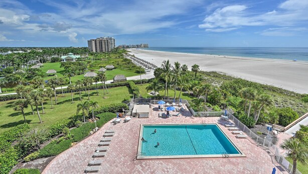 Un resort con piscina, spiaggia e palme.