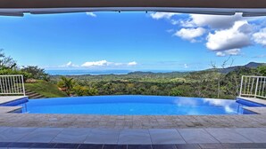 Una piscina con vista su un paesaggio montuoso e l'oceano.